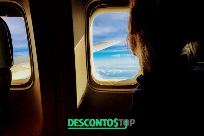cupom desconto - mulher olhando pela janela avião